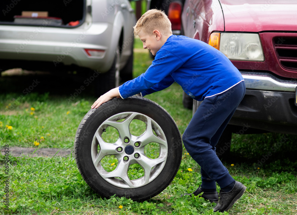 caucasian boy is rolling a car wheel caucasian boy is rolling a car wheel