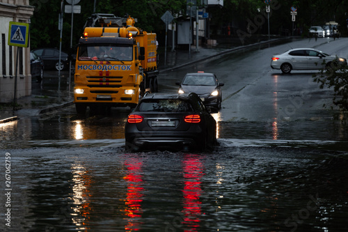 Cars drive through the flooded city
