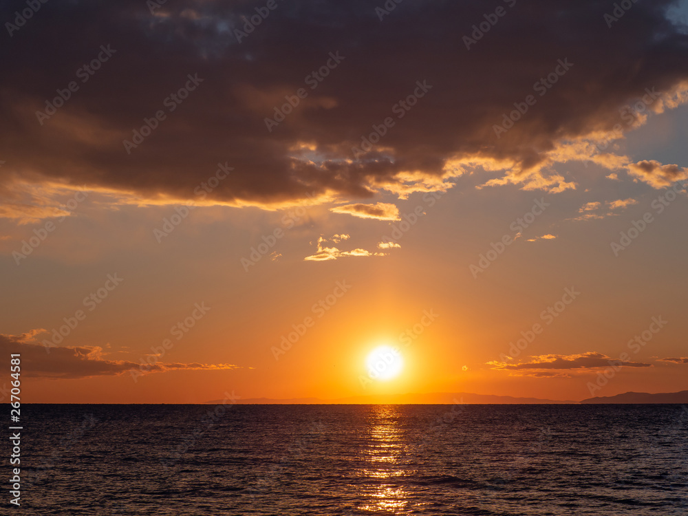 Bright orange sunset over the sea - islands on the horizon