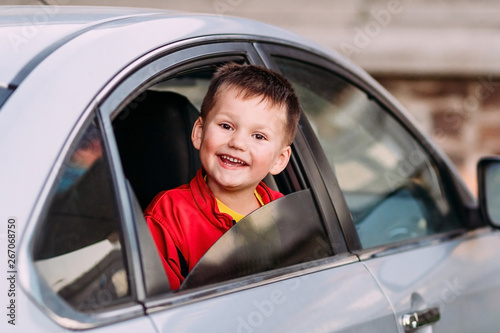 a laughing child looks out of an open car window