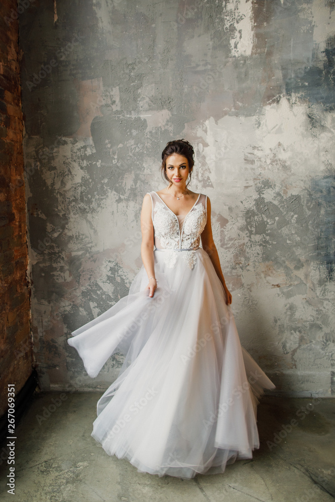 portrait of a young beautiful wedding bride in a beautiful stylish dress on a gray background