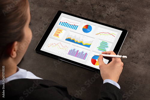 Elegant business woman making diagrams on tablet with pencil
