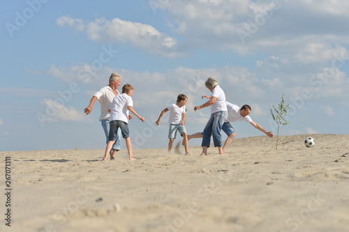 Portrait of family playing football on a beach in summer day