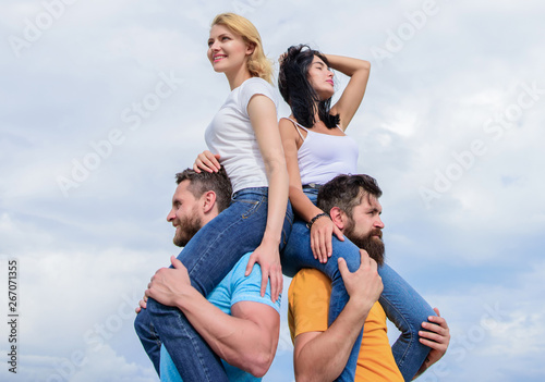 Taking real pleasure. Playful couples in love smiling on cloudy sky. Loving couples having fun activities outdoor. Loving couples enjoy fun together. Happy men piggybacking their girlfriends