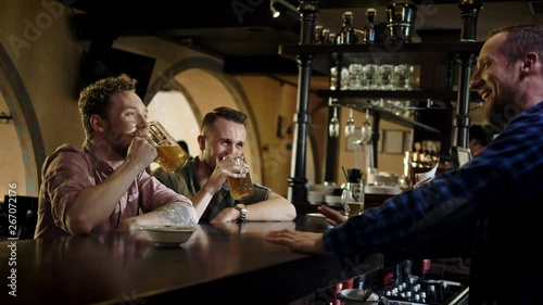 Cheerful friends drinking draft beer in a pub