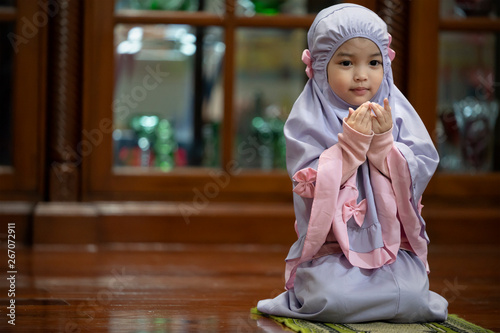 Muslim kid girl wearing Hijab praying Dua during Ramadan period. The concept is Islam,Dua,religion,worship and sin.