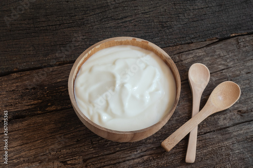 Natural homemade plain organic yogurt in wood bowl on wood texture background