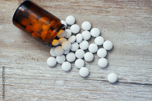 Set of round white pills. Many pills. Yellow glass bottle on wooden table. Aspirin. 