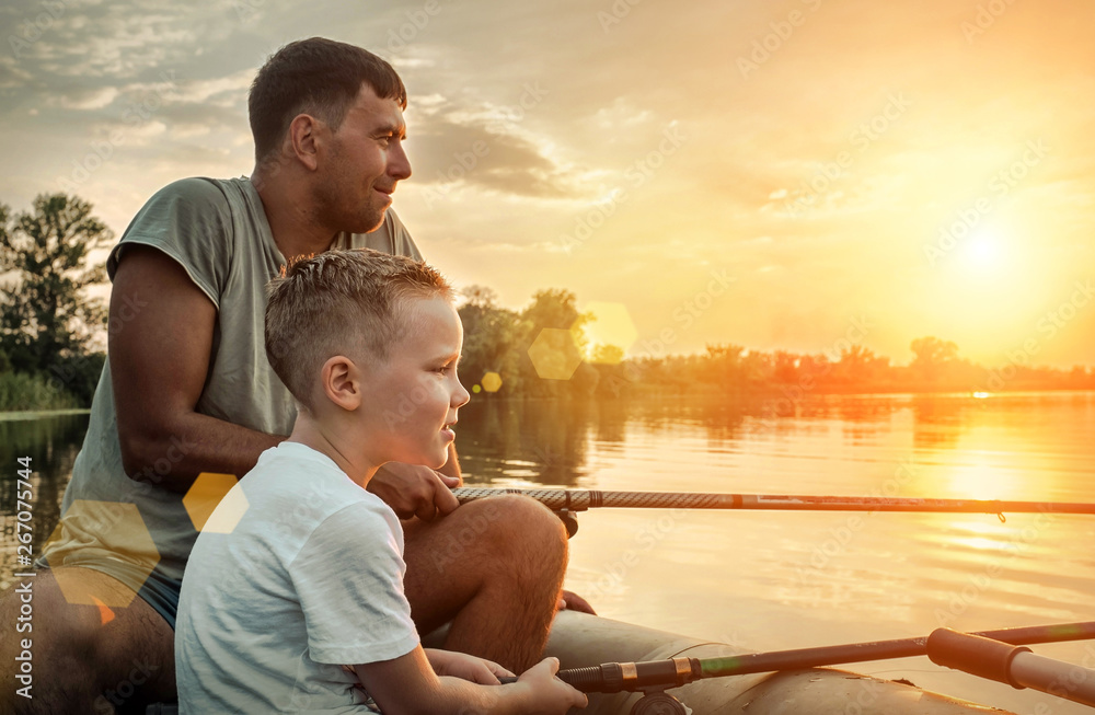 Happy Father and Son together fishing from a boat at sunset time - obrazy, fototapety, plakaty 