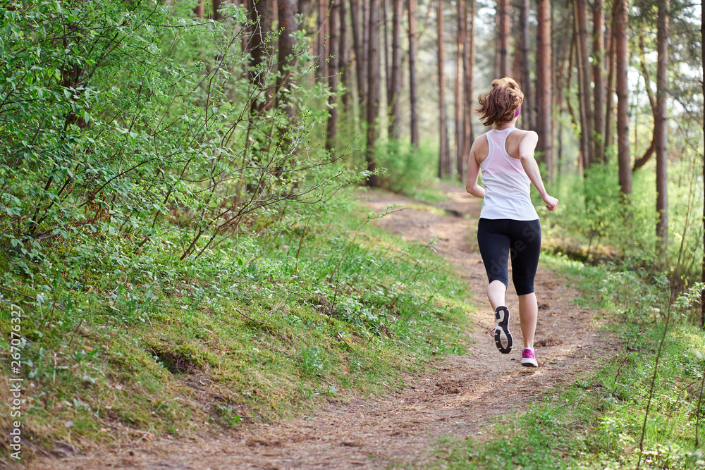 Athletic young woman in pink sneakers run in spring forest Athletic young woman in pink sneakers run in spring forest