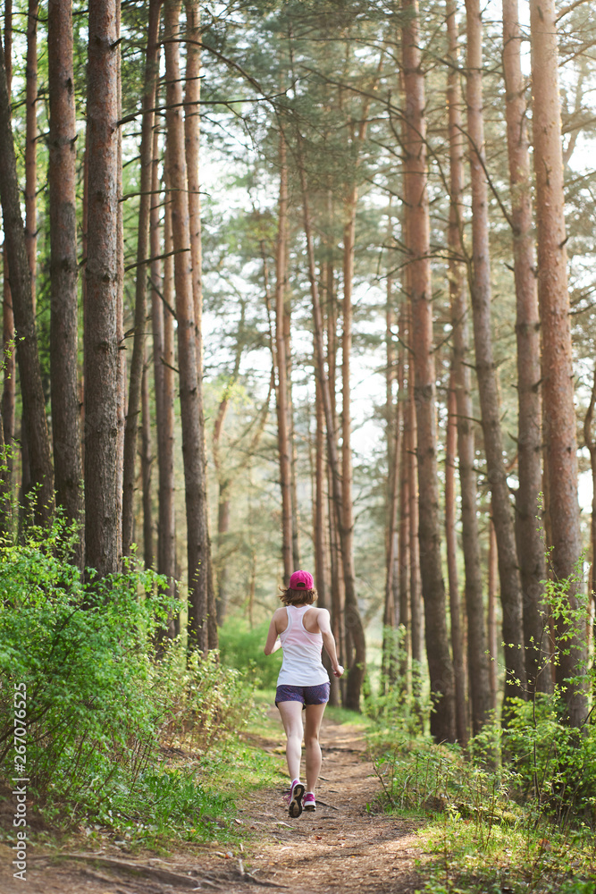 Athletic young woman in pink sneakers run in spring forest Athletic young woman in pink sneakers run in spring forest
