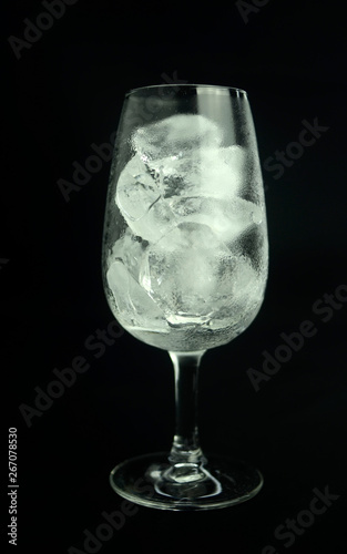 Ice cube in wine glass on black background