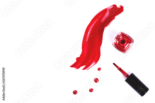 Red nail polish drops and strokes as samples, bottle and brush isolated on white background with copy space for text. Beauty, fashion and woman lifestyle concept.