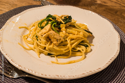 Homemade Spaghetti with Baby Spinach and Chicken at Dinner Table with Glass of Wine. photo