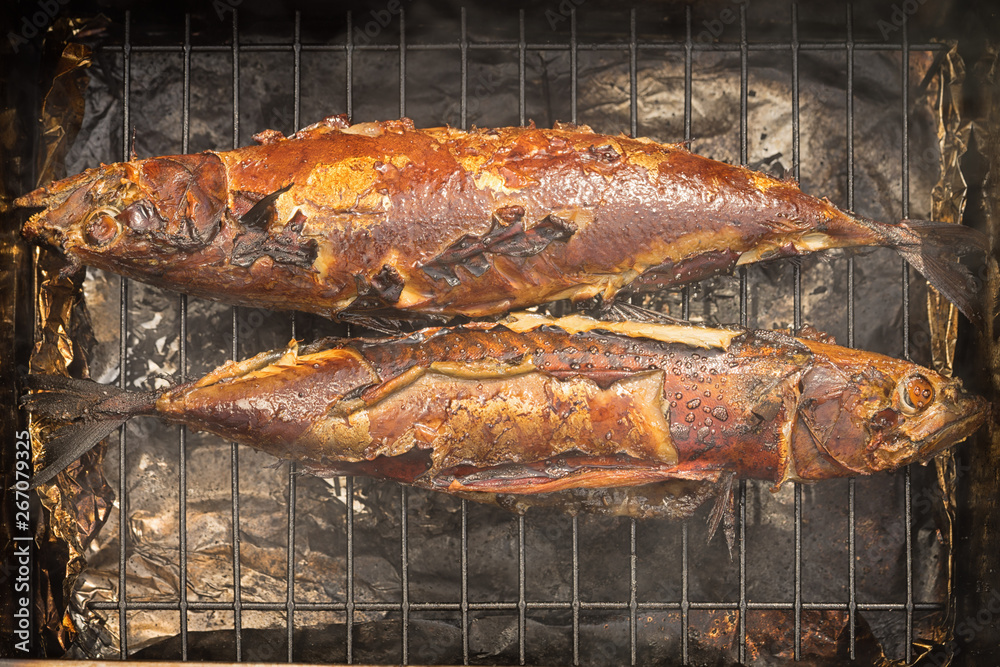Cooking smoked scomber on a grill, two fish , top view.