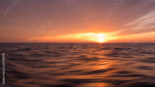 Picturesque orange sunset over water surface.