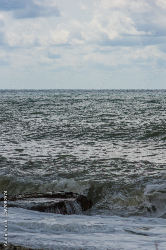 Fototapeta premium sea landscape is a pebbly beach with waves in white foam