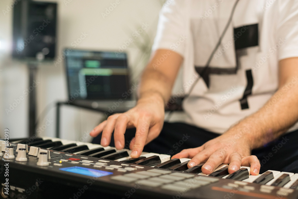 Fototapeta premium Close up of musician playing midi keyboard in home music studio.