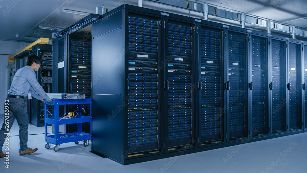 In the Modern Data Center: Team of IT Technicians Working with Server Racks, Running Maintenance and Diagnostics, Checking Networking and Cloud Computing Optimal Functioning.
