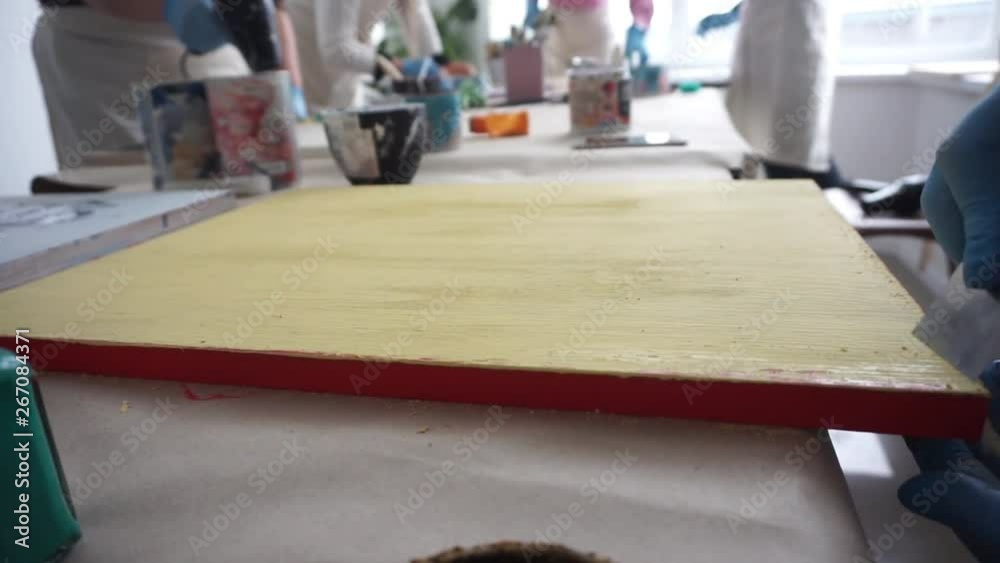 The artist scratches the paint with a spatula. Paint cans. Yellow paint. The artist scratches the paint with a spatula. Paint cans. Yellow paint.