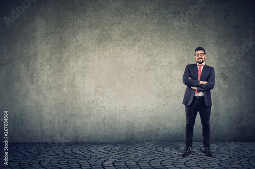 confident smiling business man standing against a wall background