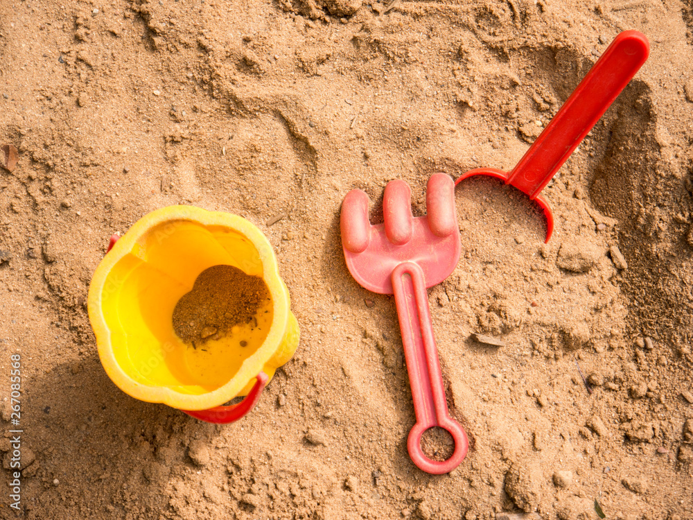 Bucket, puddle and rake in kid's sandbox top view Bucket, puddle and rake in kid's sandbox top view