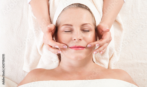 portrait of beautiful woman in spa environment. middle aged woman doing facial massage in a spa salon
