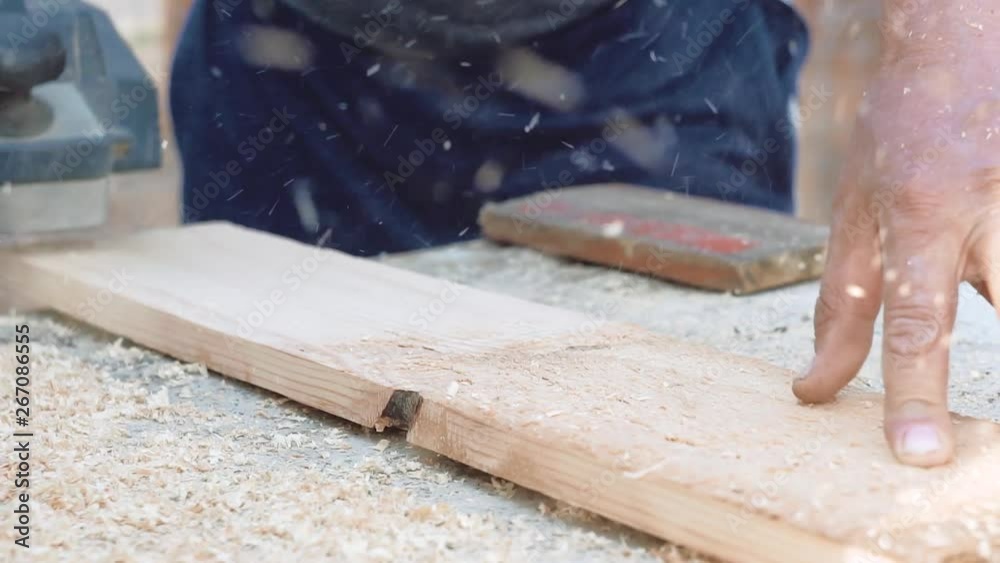 a man planes a plank with an electric plane, wood chips