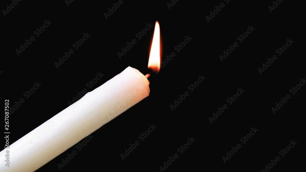 White long candle close-up. The flame of a candle slowly shakes from the air. Darkness around White long candle close-up. The flame of a candle slowly shakes from the air. Darkness around