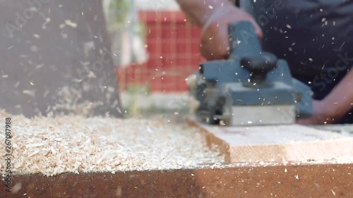 a man planes a plank with an electric plane, wood chips