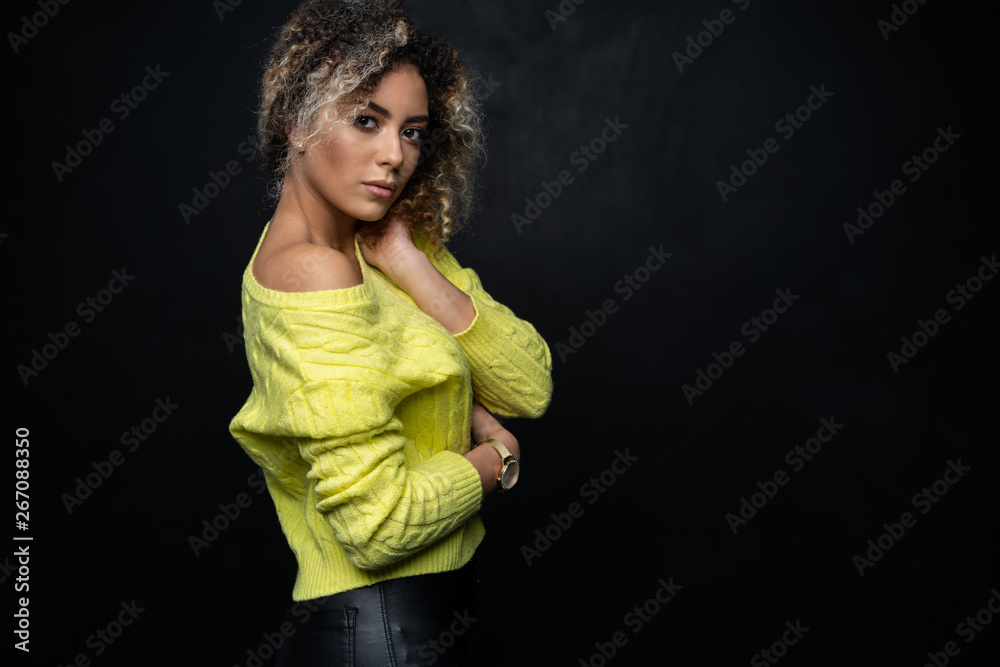 Portrait of a beautiful black female fashion model with curly hair over black background. Portrait of a beautiful black female fashion model with curly hair over black background.