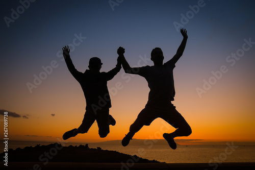 I love you, dad! Handsome young man outdoor with his little cute boy are having fun and jumping on sunset. Full length photo of optimistic men backlight jumping together isolated. Happy Father's Day