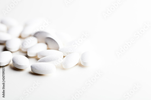 Pile of white drug pills laying on white background.