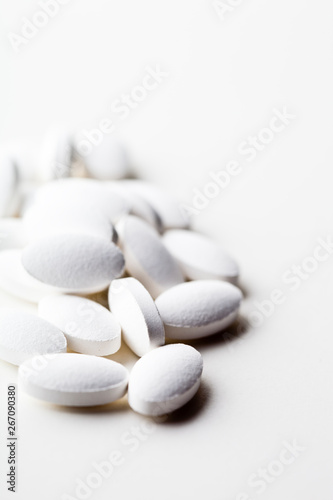 Pile of white drug pills laying on white background.