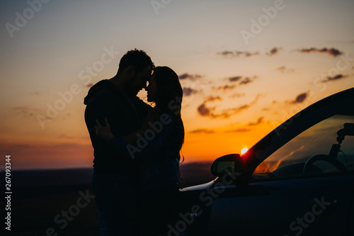 Silhouette kissing men and women at sunset in the car. A couple in love travels by car at sunset.