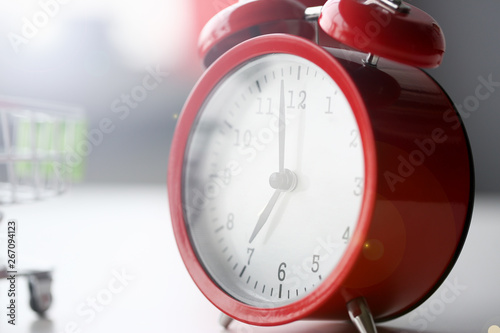 Red alarm clock set at seven in the morning closeup