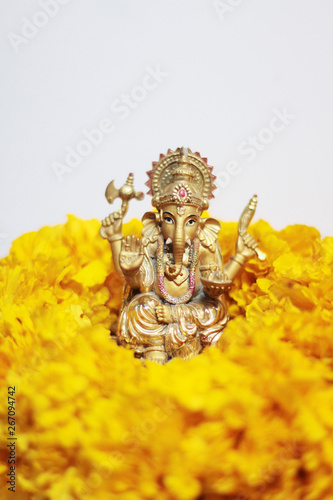 Gold Ganesha Statue god is the Lord of Success God of Hinduism on Marigold flowers Isolated on white background. © cocorattanakorn