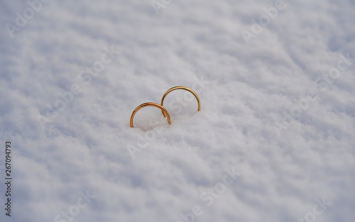 Two gold wedding rings placed in the fresh snow.