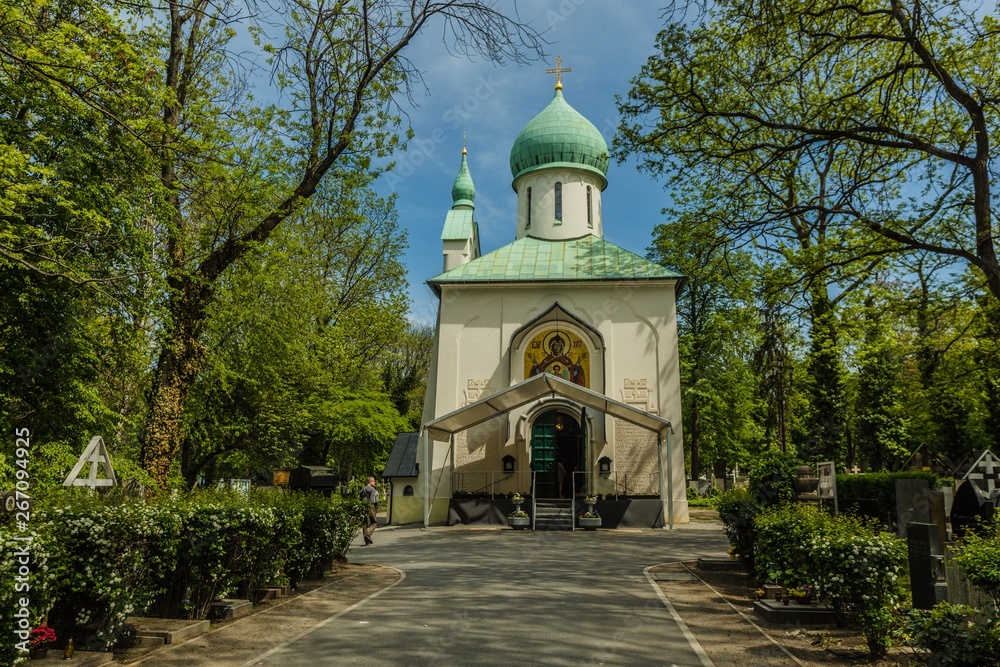 Fototapeta premium Prague, Czech Republic - May 8 2019: Orthodox church, the Sanctuary of the Dormition of the Theotokos at Olsany cemetery in Zizkov district. Fresh green colored trees, sunny day, blue sky.