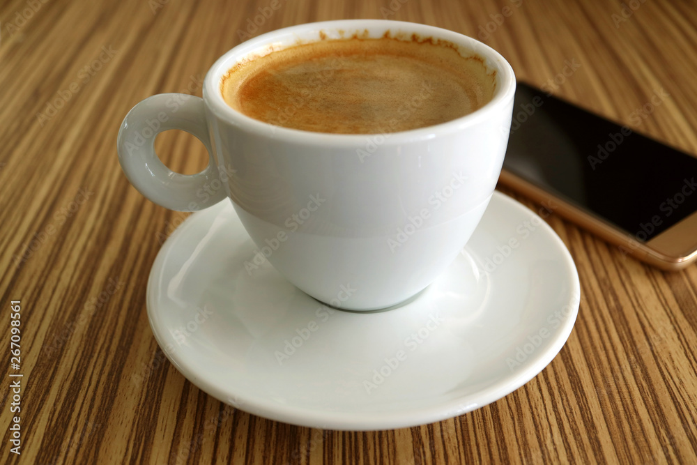 One Cup of Hot Black Coffee with a Blurry Cellphone in Background One Cup of Hot Black Coffee with a Blurry Cellphone in Background