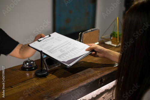Receptionist's sent the documents to guest for signing and filling up form check-in process.Hotel concept.