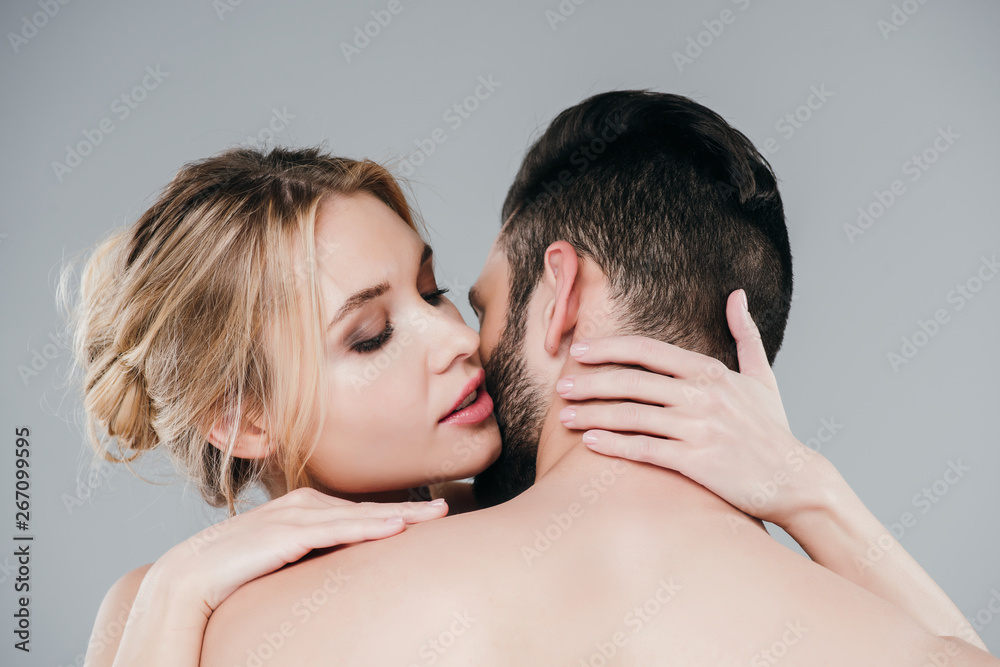 attractive blonde girl embracing shirtless man on grey