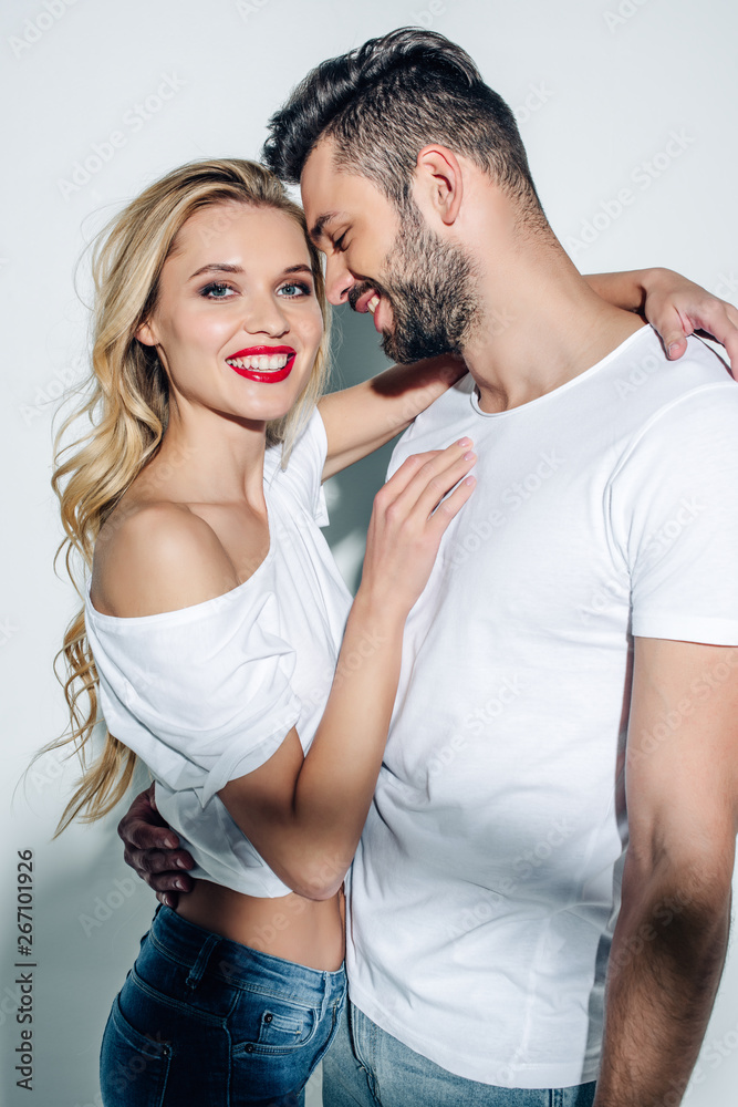 happy blonde woman hugging cheerful bearded man smiling on white happy blonde woman hugging cheerful bearded man smiling on white