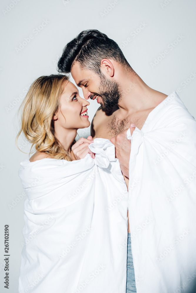 happy couple looking at each other while holding blanket on white happy couple looking at each other while holding blanket on white