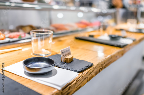 Japanese restaurant sign in traditional style, interior asian sushi wooden bar counter, menu, bowl, glass and napkin setting typical izakaya closeup