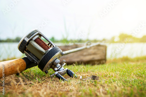 Fishing activities. rod with baitcasting reel on the grass wait for the fish to stick or eat to the hook on natural white sky background and copy space.