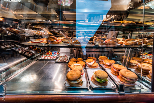 Display of store shop selling Italian panini sandwiches deli and croissants on tray platter glass window in large bakery