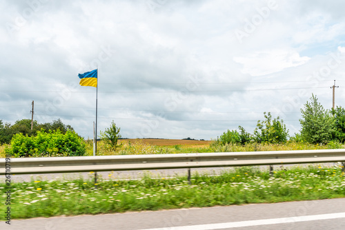 Ukrainian flag sign by road in Rivne, Ukraine Western country on highway street waving in windy cloudy day