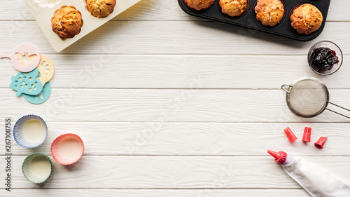 top view of delicious muffins and baking tools on wooden table with copy space