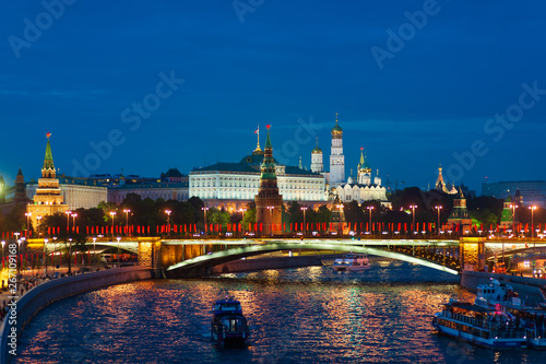  View of the Moscow Kremlin and the Big Stone bridge (Bolshoy Kamenniy bridge) decorated with flags. The lights of the night city reflected in the Moscow river.